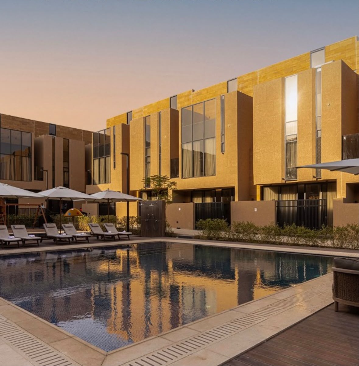 Al Habib compound pool deck at sunset with amber-lit facades