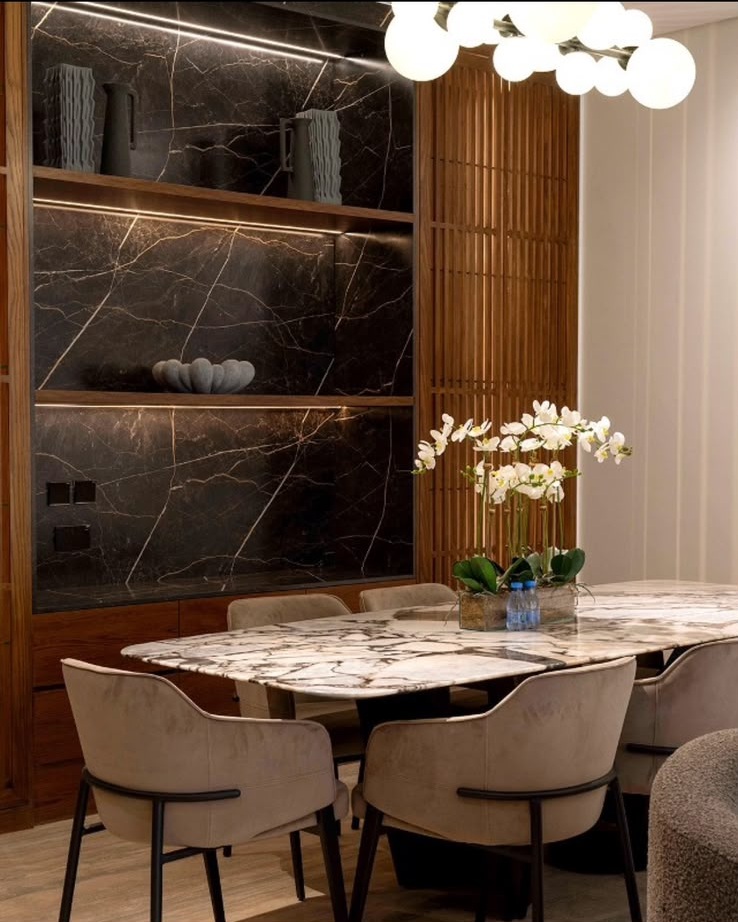 Al Habib villa dining room with veined marble table and black stone feature wall
